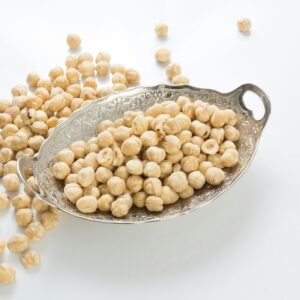 Close-up of peeled hazelnuts in a vintage silver dish on white background, perfect for recipes.